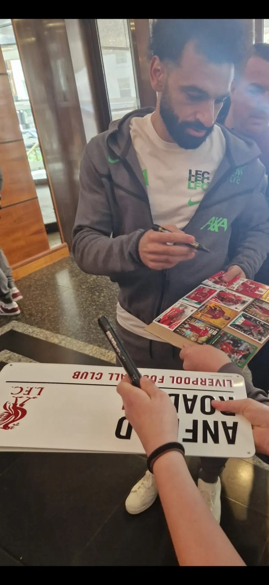Liverpool player signing an Anfield Road sign