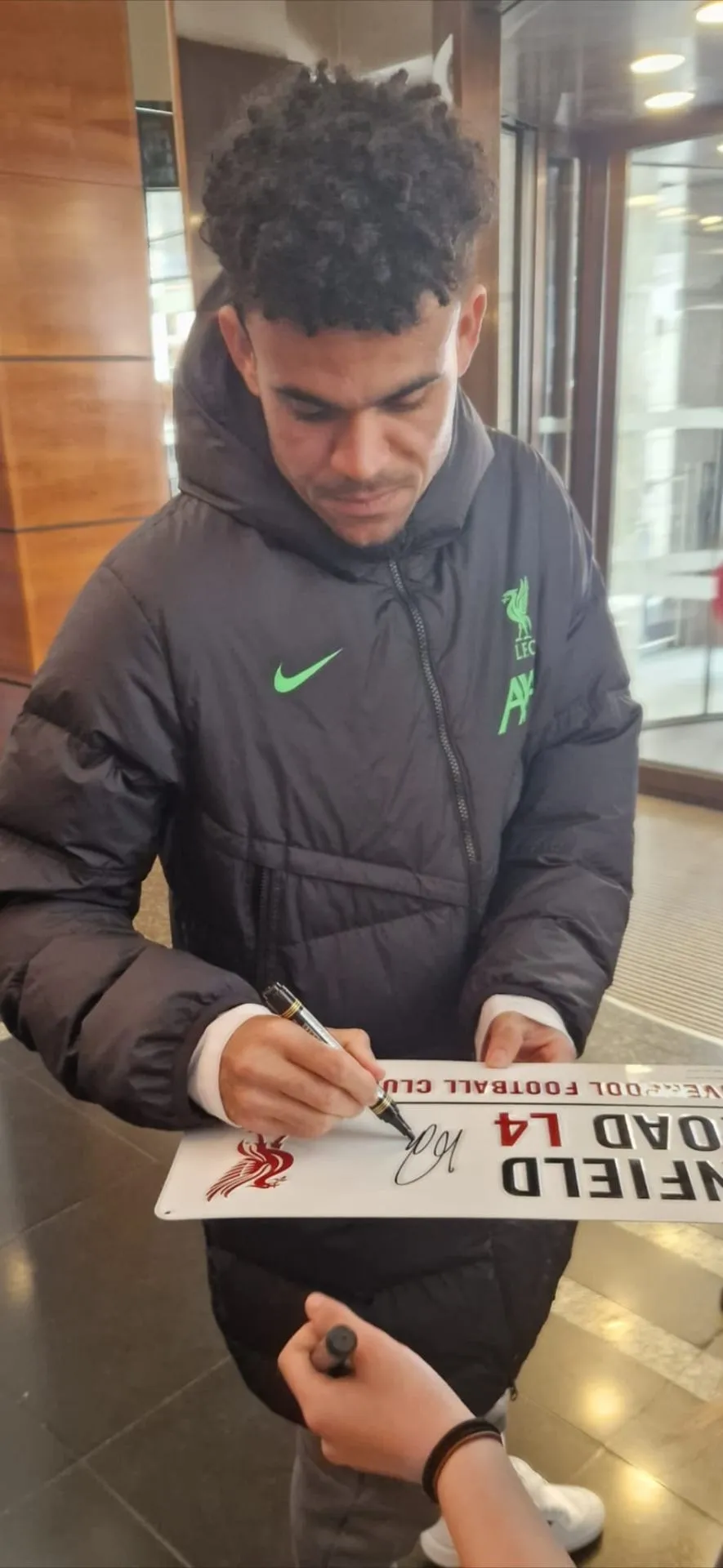 Liverpool player signing an Anfield Road sign
