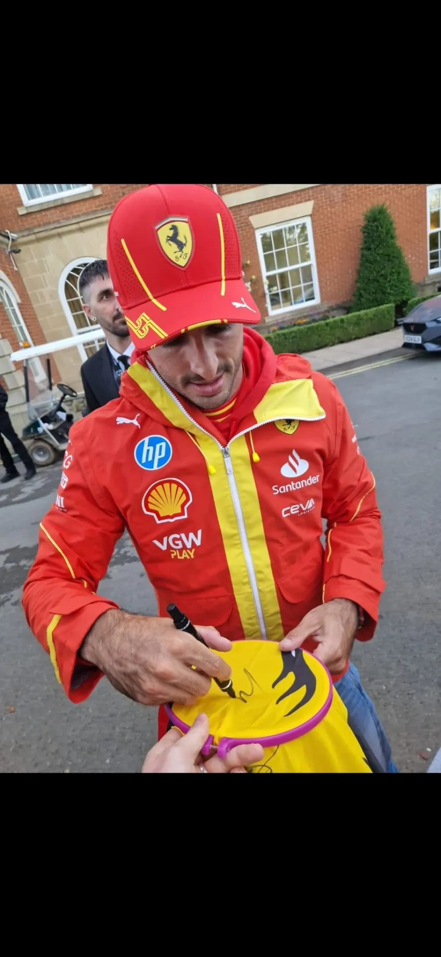 Ferrari F1 driver Carlos Sainz signing a cap