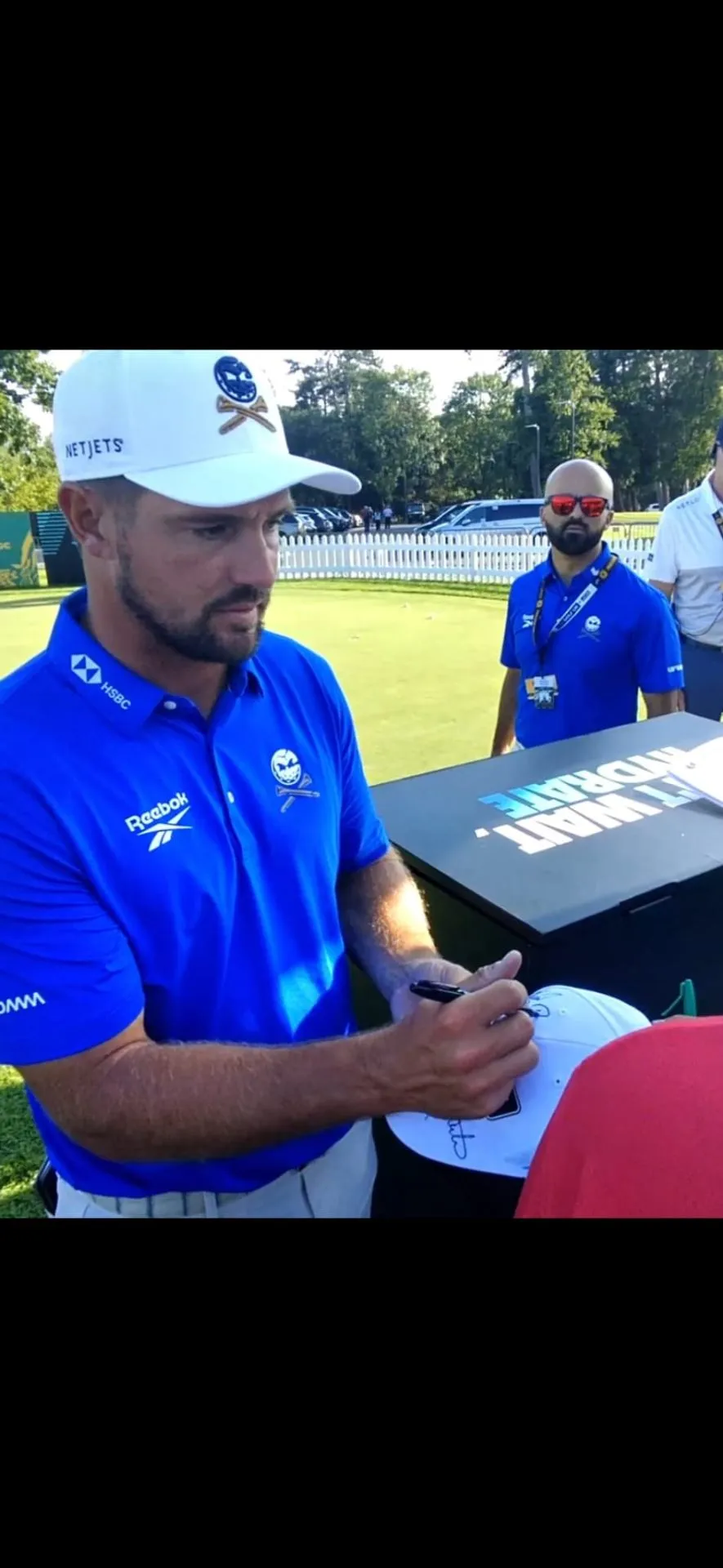 Golfer signing a cap at a tournament